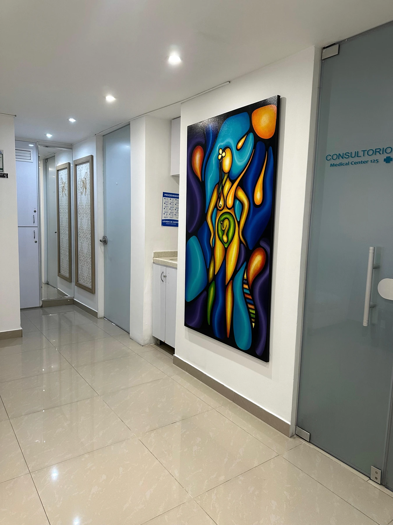 Corredor interior de Medical Center 125 con acceso a los consultorios y una obra de arte en la pared.