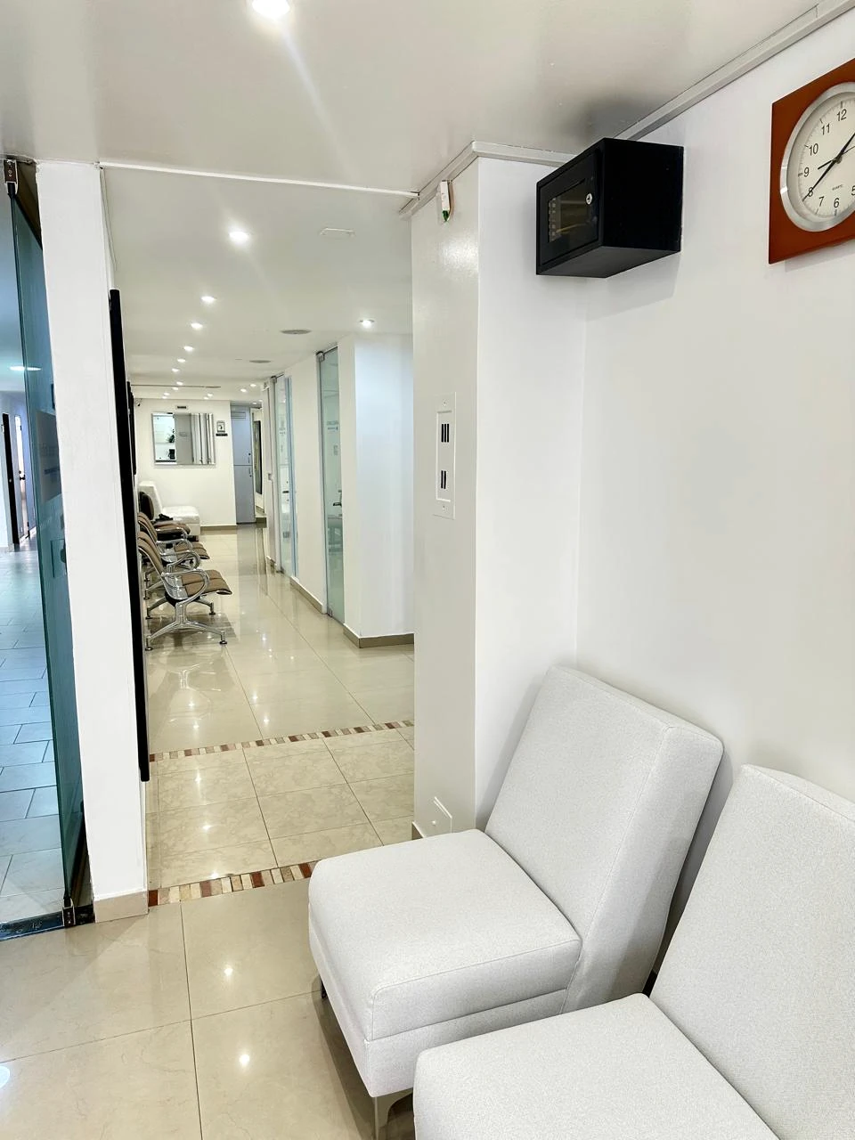 Sala de espera de Medical Center 125 con sillas claras junto al corredor interior.
